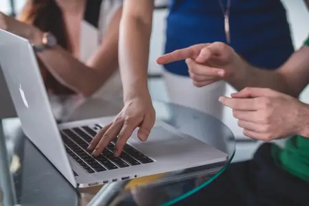 Two people collaborating on an Apple laptop